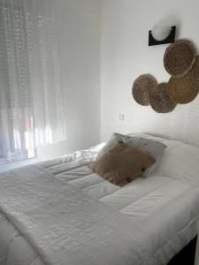 ein weißes Schlafzimmer mit einem Bett mit Hüten an der Wand in der Unterkunft Le Chic in Lourdes