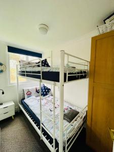 サンダウンにある“BLISS ON THE BAY ” chalet in Sandown Bay Holiday Parkの窓のある部屋に二段ベッドが2つある +12枚の写真