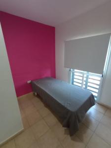 a bed in a room with a purple wall at Edificio Castelli 90 in Chumillo