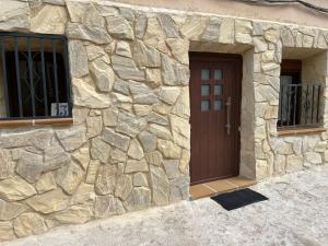a stone building with a brown door and two windows at La Rambla in Albarracín