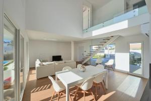 a dining room and living room with a white table and chairs at Aroeira Villa w/ Pool near Beach, By TimeCooler in Aroeira