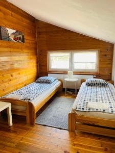two beds in a room with wooden walls at Pokoje Slawin in Lublin