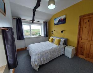 a bedroom with a bed with yellow walls and a window at The Barn - Cosy cottage with Countryside views in Ludchurch