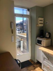 una cucina con finestra e bancone con forno a microonde di Logement à Brive avec terrasse et climatisation - près de la gare et du centre-ville - Wifi et Stationnement gratuit a Brive-la-Gaillarde