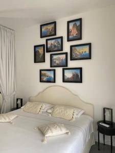 a bedroom with a white bed with pictures on the wall at Vittorio Emanuele Top Suite in Capri