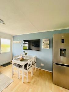 eine Küche mit einem weißen Tisch und einem Kühlschrank in der Unterkunft “SEA HEAVEN “ chalet in Sandown Bay Holiday Park in Brading