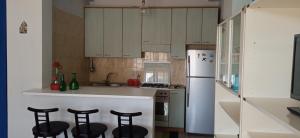 une cuisine avec des placards blancs et des tabourets de bar noirs dans l'établissement Home Tropicana, à Mascali