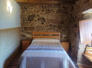 een slaapkamer met een bed in een stenen muur bij Casa do Xurés in Maus de Salas