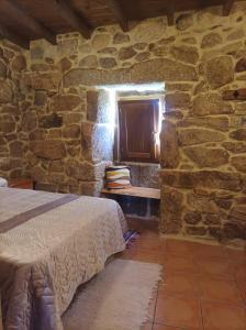a bedroom with a bed and a window in a stone wall at Casa do Xurés in Maus de Salas
