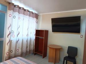 Schlafzimmer mit einem Bett, einem TV und einem Stuhl in der Unterkunft HOSPEDAJE SAMAY WASI (AYACUCHO) in Ayacucho