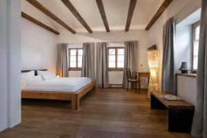 1 dormitorio con cama, mesa y ventanas en Gasthaus Unterwirt en Fridolfing