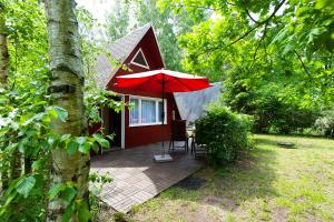 a red cabin with a table and an umbrella at Ferienhaus Katharina in Malschwitz