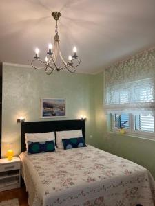 - une chambre avec un grand lit et un lustre dans l'établissement Villa Mare Apartments, à Tivat