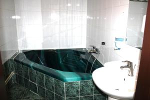 ein Badezimmer mit einer grünen Badewanne und einem Waschbecken in der Unterkunft Hotel Central in Český Těšín