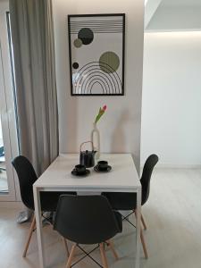 Biały stół z krzesłami i wazonem na nim w obiekcie Apartament z garażem blisko dwóch jezior na Warmii i Mazurach w mieście Biskupiec