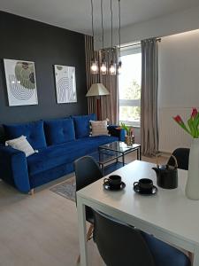 a living room with a blue couch and a table at Apartament z garażem blisko dwóch jezior na Warmii i Mazurach in Biskupiec