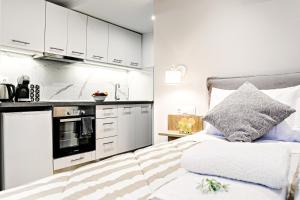 a bedroom with a bed and a kitchen with white cabinets at Ionian Citizen Atelier in Corfu Town