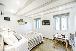 a white bedroom with a bed and a table at Ionian Citizen Atelier in Corfu Town