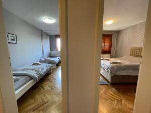 a room with three beds in a room with a hallway at Idealapartments LLC 8 in Pristina