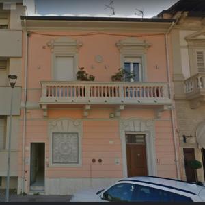 a building with a balcony and a car parked in front at Magis Ac Magis Bedrooms Versilia in Viareggio