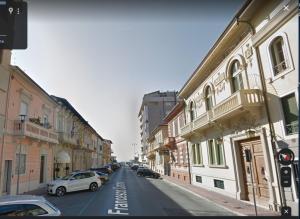 une rue de la ville avec des voitures garées sur le côté de la route dans l'établissement Magis Ac Magis Bedrooms Versilia, à Viareggio