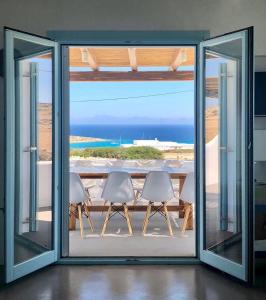 a room with a view of the ocean through sliding glass doors at Blue Harpist Villas in Koufonisia
