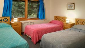 een slaapkamer met twee bedden en een raam bij Cabañas Carelmapu in Bariloche