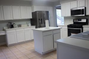 a kitchen with white cabinets and a stainless steel refrigerator at Amazing 4 Bedroom House with nice Backyard in Littleton