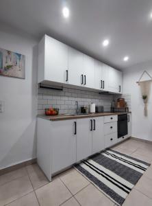 a white kitchen with white cabinets and a sink at Stegna Rita's apartment in Archangelos