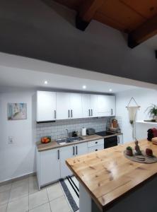 a kitchen with white cabinets and a wooden table at Stegna Rita's apartment in Archangelos