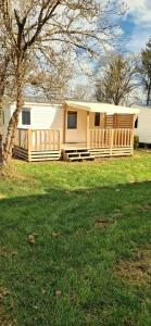 a house with a porch and a tree in a field at Mobile home in Boofzheim +56 photos
