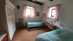 a bedroom with two beds and a table and two windows at Rustico Pult in Someo