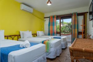 3 camas en una habitación con una pared amarilla en Pousada Barra Sol, en Barra de São Miguel