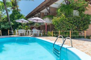 a swimming pool with chairs and umbrellas next to a house at Pousada Barra Sol in Barra de São Miguel