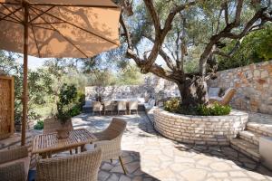 a patio with a tree and tables and chairs at Olivea Premium Holiday Homes in Stavros
