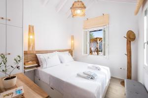 Olivea Premium Holiday Homes في Stavros: غرفة نوم بيضاء بها سرير ونافذة