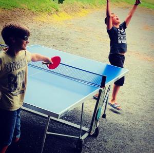 dos chicos jugando ping pong en una mesa de ping pong en La Ferme Parrinet - Gîte et Chambres d'hôtes, en Saint-Martin-Laguépie
