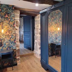Habitación con puertas azules y paredes cubiertas de papel pintado colorido. en La Ferme Parrinet - Gîte et Chambres d'hôtes, en Saint-Martin-Laguépie