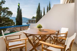 un tavolo in legno e sedie sul balcone. di Del Mar Luxury Apartment 30m From The Beach a Porto Rafti