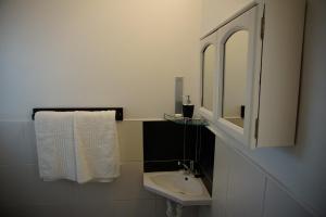 a white bathroom with a sink and a mirror at Two Door Cottage in Cape Town