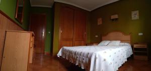 um quarto com uma cama branca e paredes verdes em Alojamientos Prada em Ballota