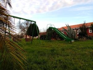um parque infantil com um escorrega verde na relva em Alojamientos Prada em Ballota