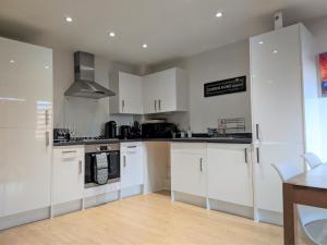 a kitchen with white cabinets and a stove at Stylish Peckham Apartment 10 Seconds From Station in London