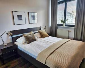 um quarto com uma cama com almofadas e uma janela em Apartamenty Arkadia by VisitWarsaw Apartments em Varsóvia
