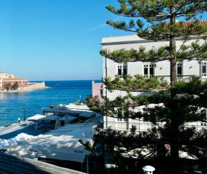a large white building with a tree in front of the water at Old Port - Bellavista Studio in Chania +13 photos