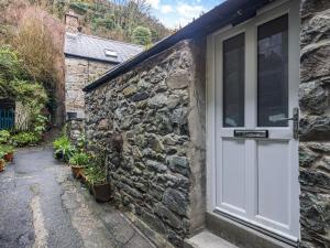 a stone house with a white door and a pathway at Llety Clyd in Barmouth