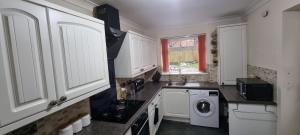 a kitchen with white cabinets and a washing machine at Spacious Large House - Very close to M1 - Walking distance to L&D Hospital - Contractor Friendly - Large groups in Luton