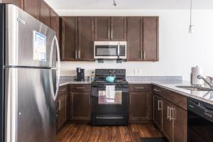 a kitchen with wooden cabinets and a stainless steel refrigerator at Stylish 1BR in at the Crossing in Indianapolis
