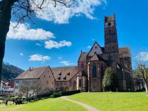 uma velha igreja com uma torre num campo verde em Le Bain du Corbeau - Schwarzwald-Villa Alpirsbach em Alpirsbach