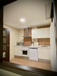 uma cozinha com armários brancos e um forno com placa de fogão em Mi Refugio em Arenas de San Pedro